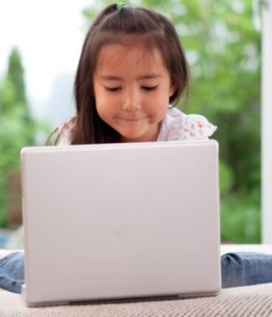 Une enfant assise devant un ordinateur portable // Source : SimpleFoto