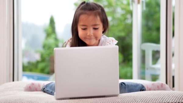 Une enfant assise devant un ordinateur portable // Source : SimpleFoto