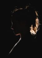 Une silhouette de fillette avec une queue de cheval, photographiée dans le noir // Source : Unsplash / Molly Blackbird 