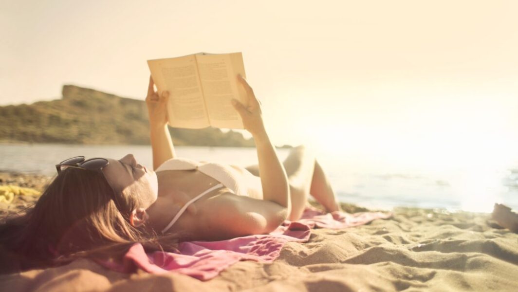 Femme en train de lire sur la plage en été // Source : PexelsAndrea Piacquadio