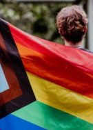 Une personne de dos, tenant le drapeau des fiertés LGBTI // Source : Emma Rahmani de baseimage
