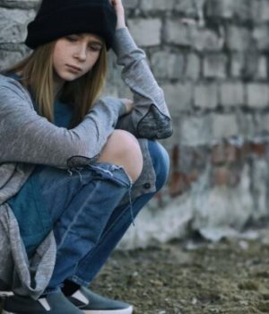 Une fille SDF assise par terre dans la rue en train de mendier // Source : pixelshot