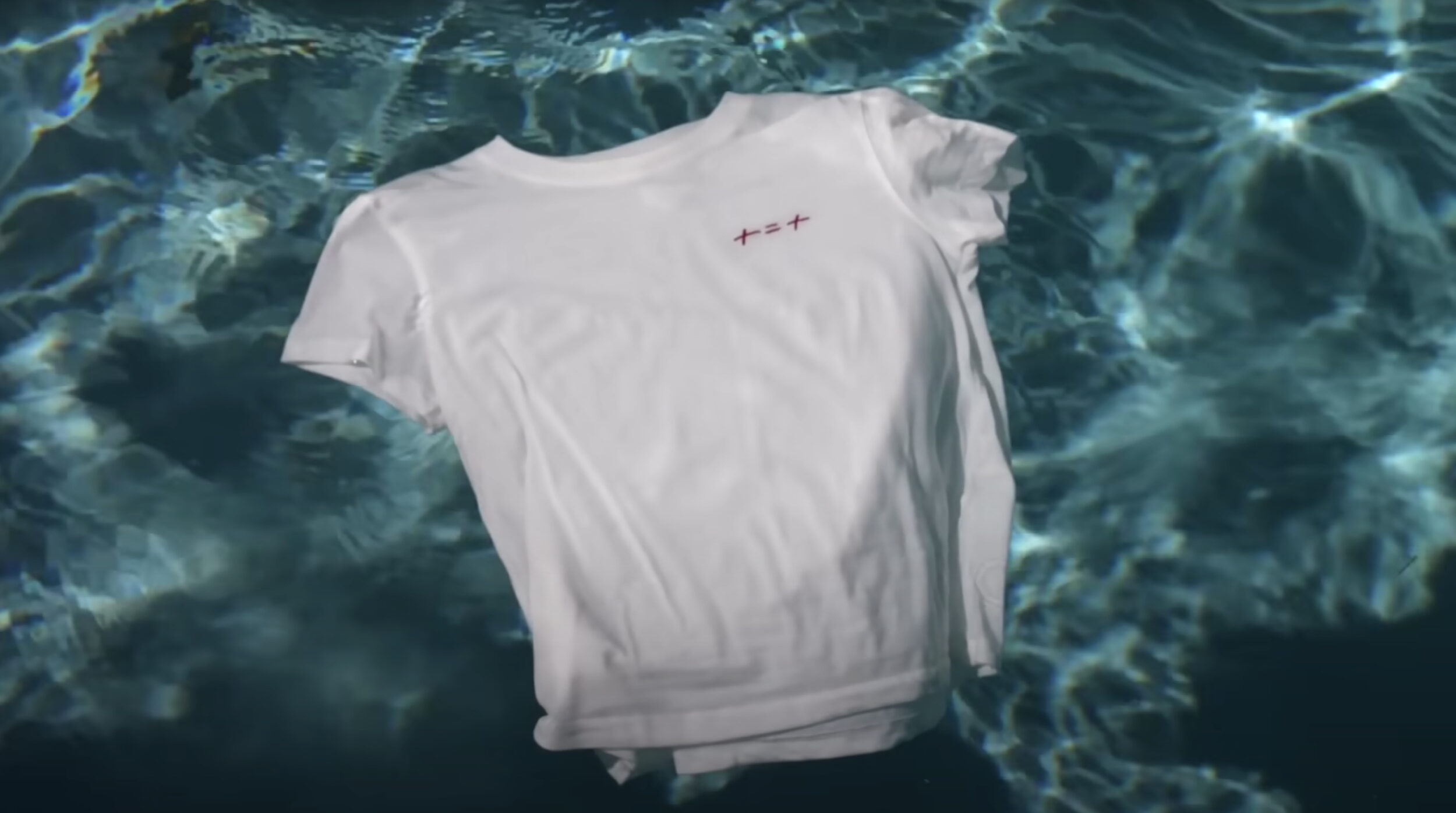Un t-shirt brodé + = + de la marque Hôtel Mahfouf de Lena Situations, flottan dans une piscine