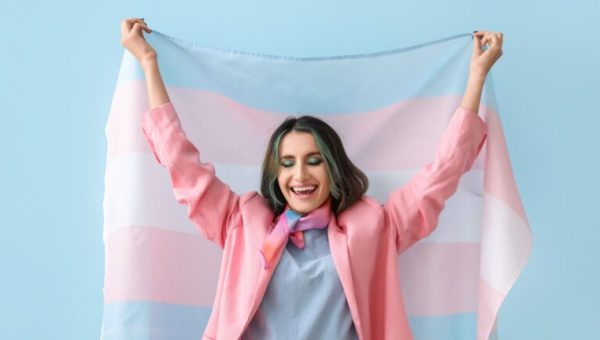 Une personne portant fièrement le drapeau des transidentités // Source : pixelshot