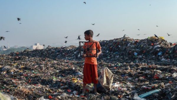 Un enfant au milieu d'une décharge à ciel ouvert pleine de pollution textile // Source :  Muhammad Amdad Hossain de Pexels