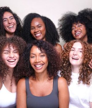 En gris, Sandrine Sophie, fondatrice de la marque Kalia Nature, entourée d'autres femmes aux cheveux texturés // Source : Kalia Nature
