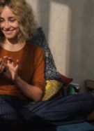 Portrait of smiling young woman sitting on bed using E-book reader