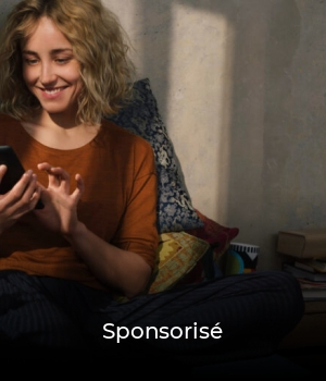 Portrait of smiling young woman sitting on bed using E-book reader