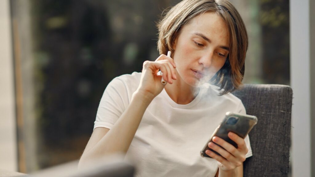 woman-smoking-while-holding-her-phone-4017434