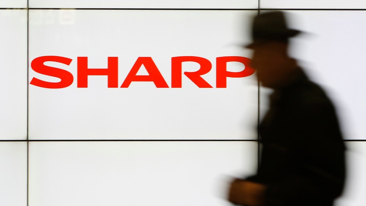 A pedestrian walks past a logo of Sharp Corp at a train station in Tokyo in this February 3, 2014 file photo. Embattled Japanese electronics maker Sharp Corp is preparing to seek aid from its two main lenders, a source with direct knowledge of the matter said, as it expects impairment losses from unprofitable businesses to mount this year.  REUTERS/Yuya Shino/Files (JAPAN - Tags: BUSINESS LOGO)