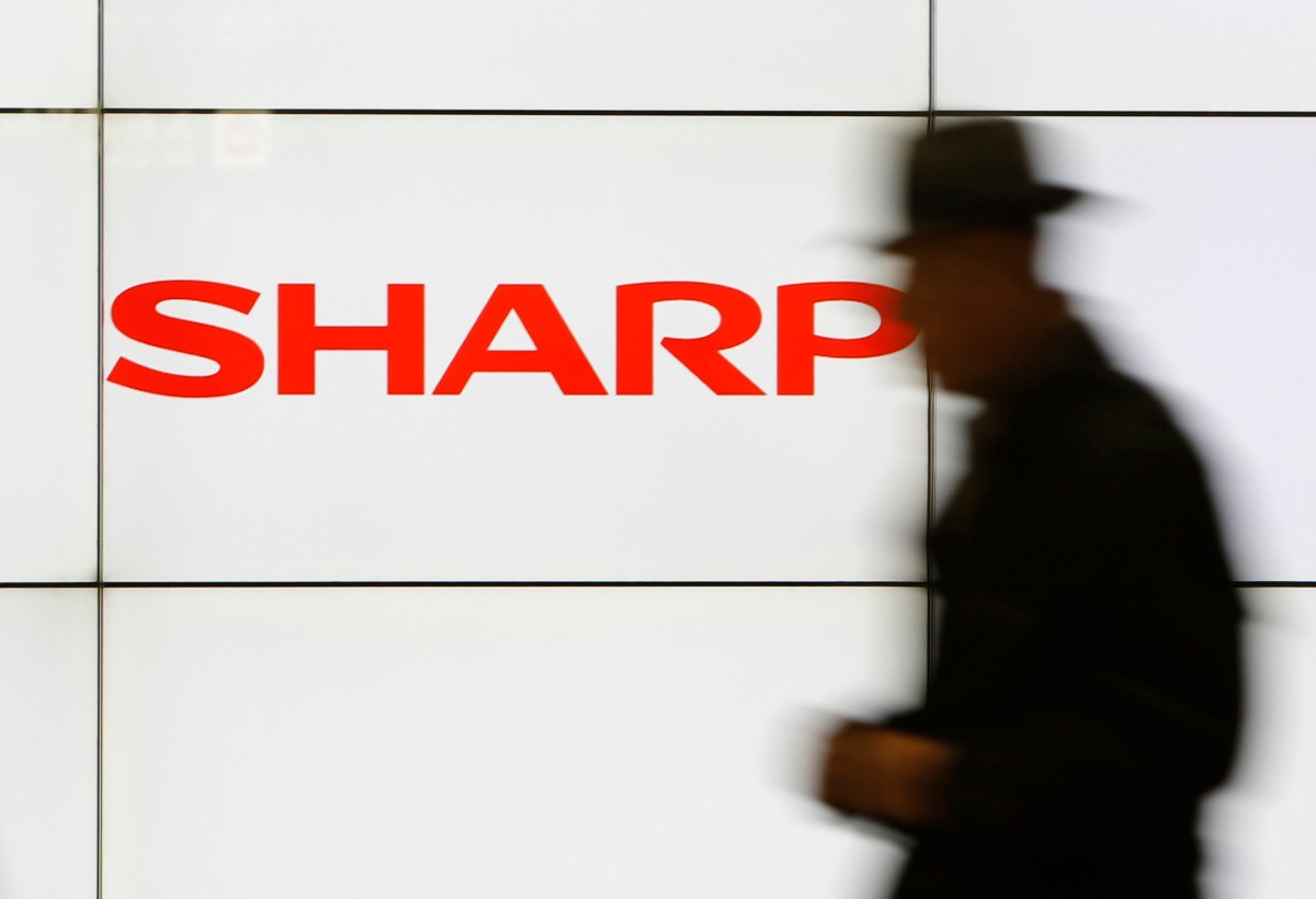 A pedestrian walks past a logo of Sharp Corp at a train station in Tokyo in this February 3, 2014 file photo. Embattled Japanese electronics maker Sharp Corp is preparing to seek aid from its two main lenders, a source with direct knowledge of the matter said, as it expects impairment losses from unprofitable businesses to mount this year.  REUTERS/Yuya Shino/Files (JAPAN - Tags: BUSINESS LOGO)