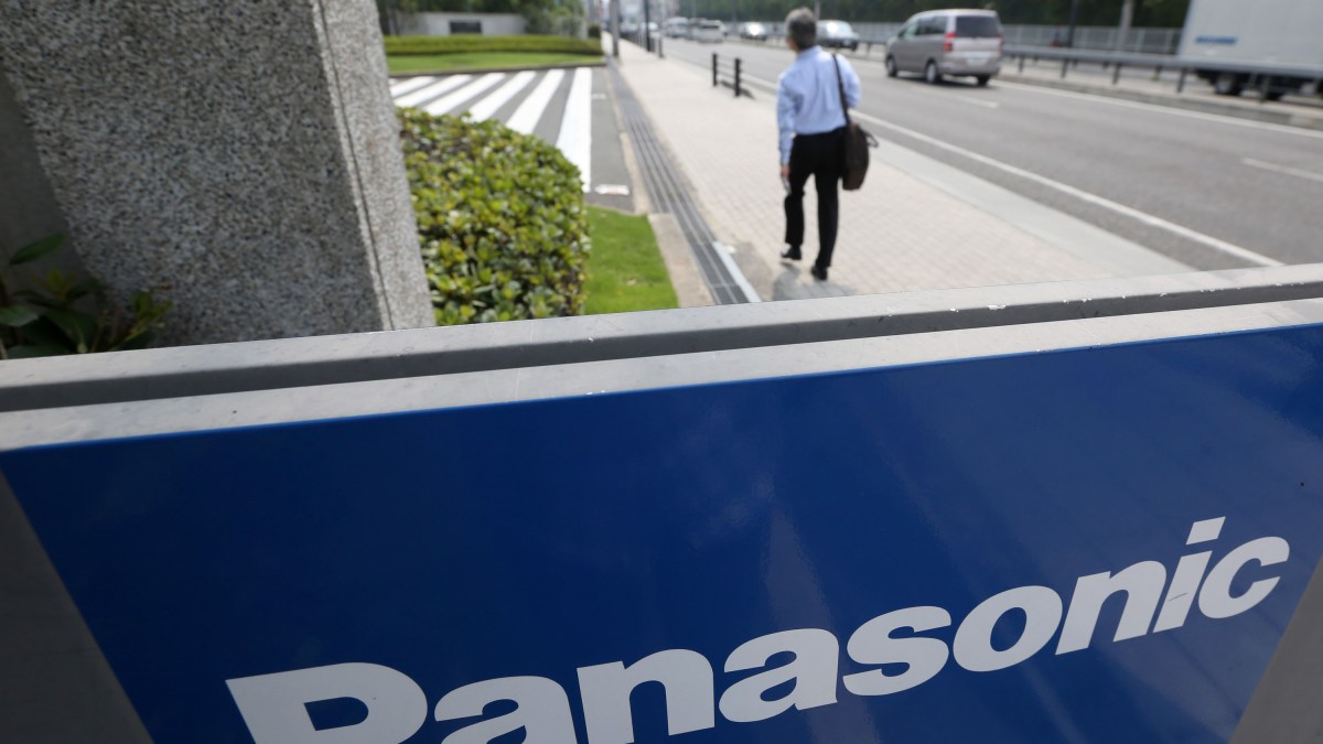 A man walks past Panasonic Corp. signage at the company's headquarters in Kadoma, Osaka Prefecture, Japan, on Wednesday, July 31, 2013. Panasonic, Japan's biggest consumer electronics maker, reported profit that exceeded analyst estimates after cutting wages, selling assets and a one-time gain from changes in pension accounting. Photographer: Tomohiro Ohsumi/Bloomberg