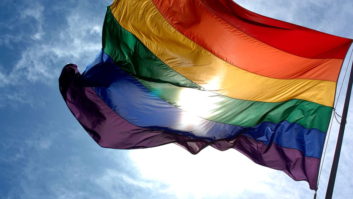 1280px-Rainbow_flag_and_blue_skies