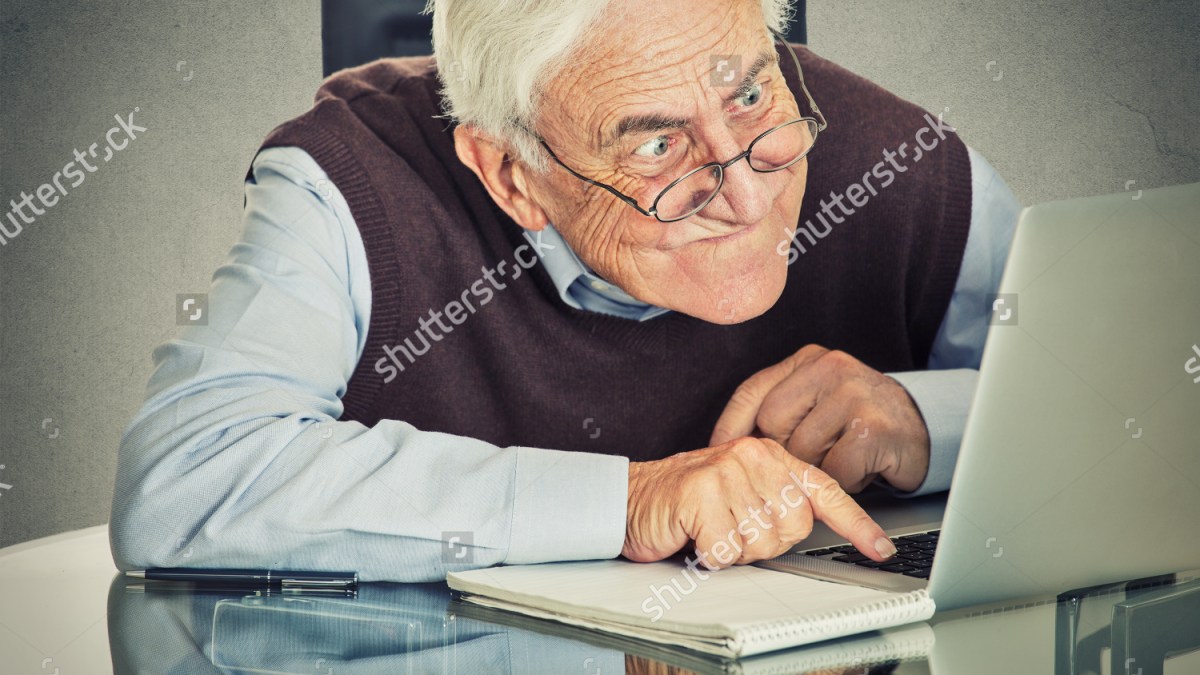 stock-photo-elderly-old-man-using-computer-sitting-at-table-isolated-on-grey-wall-background-senior-people-and-252858463