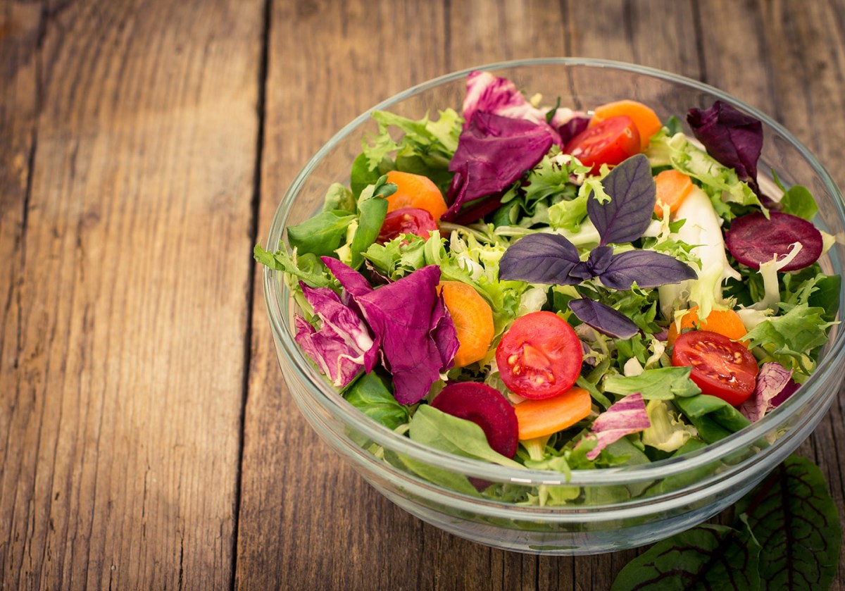 Fresh mixed salad in the bowl on the wooden table