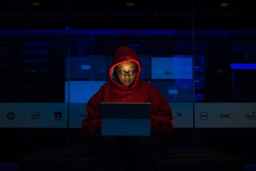 Une femme qui ne pirate probablement pas un réseau WiFi mais qui a une capuche de hackeuse. // Source : WoC In Tech