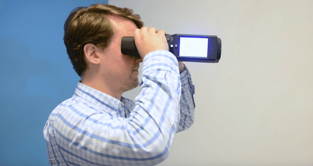 Un homme tient les binoculaires QuickSee devant ses yeux. 