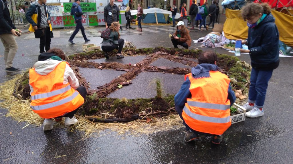 Les militants bâtissent des zones « naturelles », avec de la terre et des plantes récupérées dans des poubelles ou offertes par des habitants. Ici, c'est le logo de XR qui est représenté. // Source : Numerama