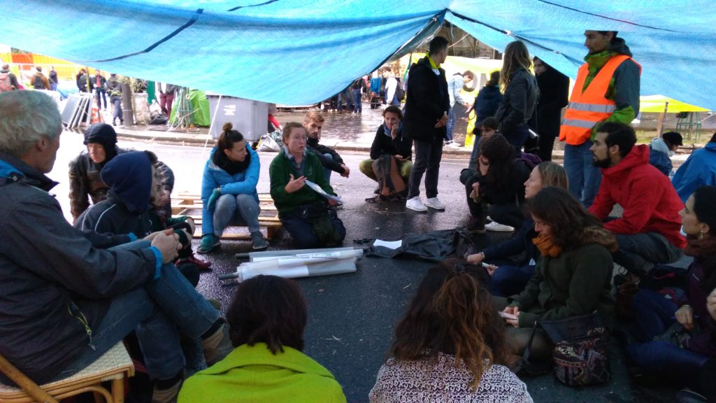 Les « zadistes » d'XR se rassemblent sous des tentes pour suivre des conférences durant lesquelles des organisateurs leur parle des objectifs du mouvement et les forment à la communication. // Source : Numerama