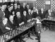 Une photo de Samuel Reshevsky, génie des échecs, prise en 1920 alors qu'il fait des parties simultanées avec des adultes (qu'il a probablement battu). // Source : Wikipedia