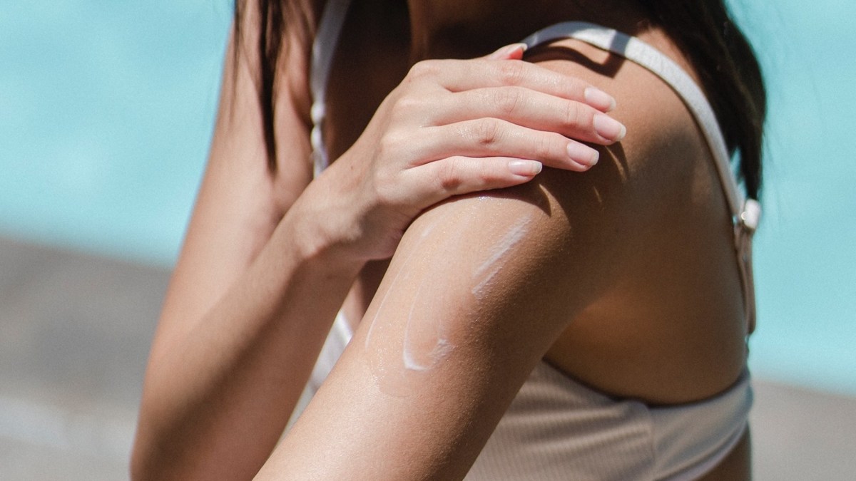 Personne au soleil appliquant de la crème solaire. // Source : Pexels