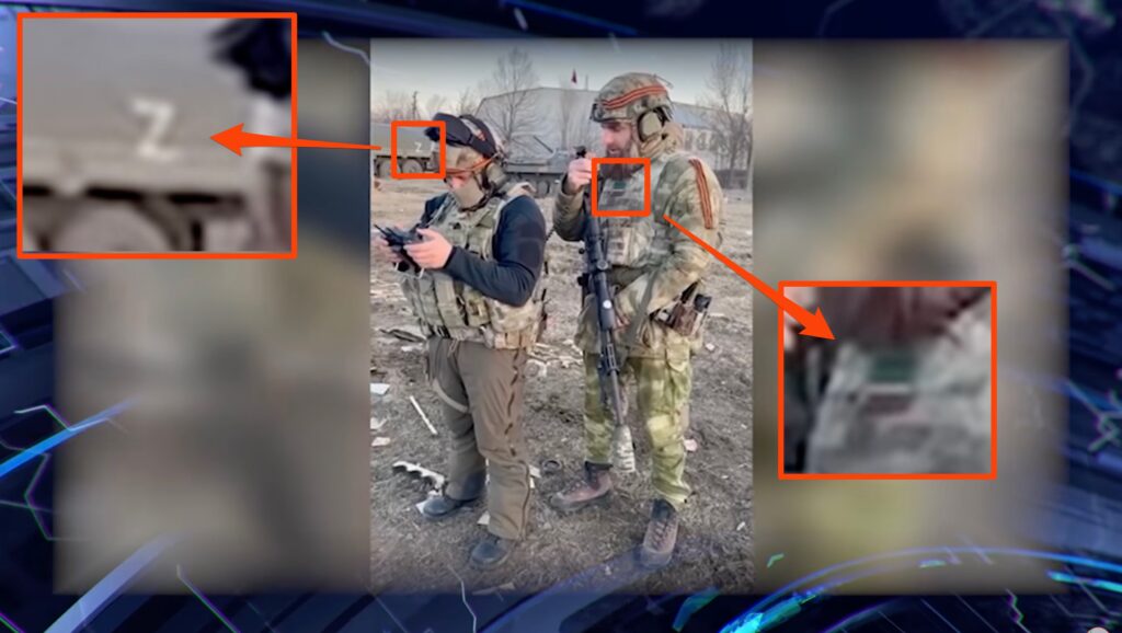 Le Z sur un char dans le fond fait penser à une association avec les troupes russes, tandis que le drapeau sur la droite est celui de la Tchétchénie // Source : YouTube/КалемПир ТВ