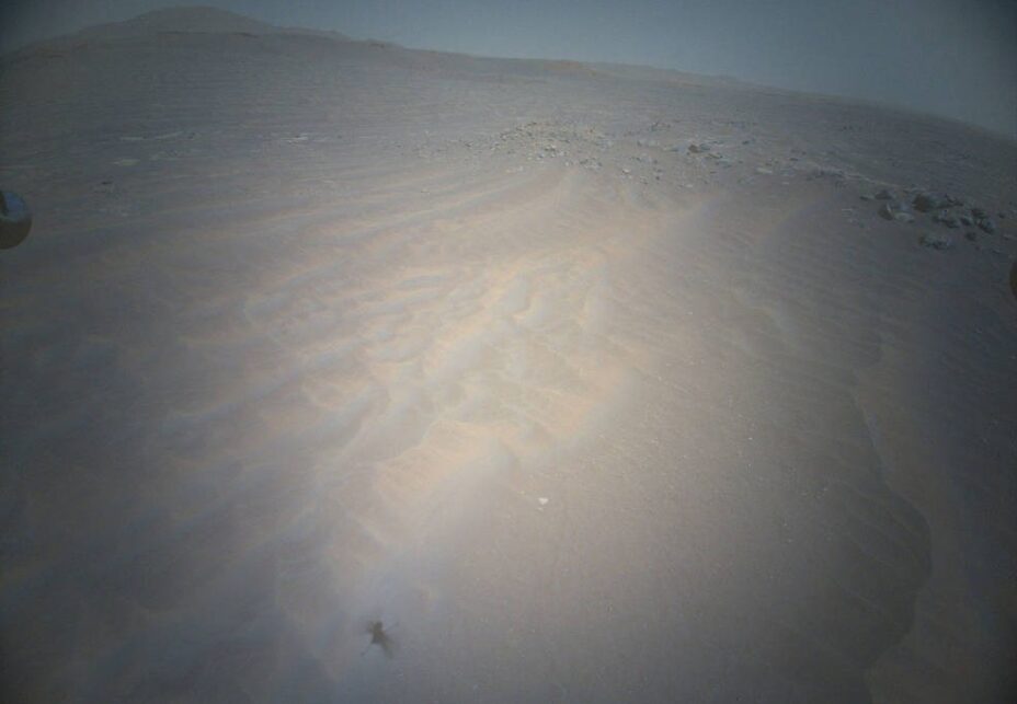 Photo prise par Ingenuity (on voit son ombre en bas) lors de son 21e vol, région martienne de Séítah. // Source : Nasa Photo prise par Ingenuity (on voit son ombre en bas) lors de son 21e vol, région martienne de Séítah. // Source : Nasa