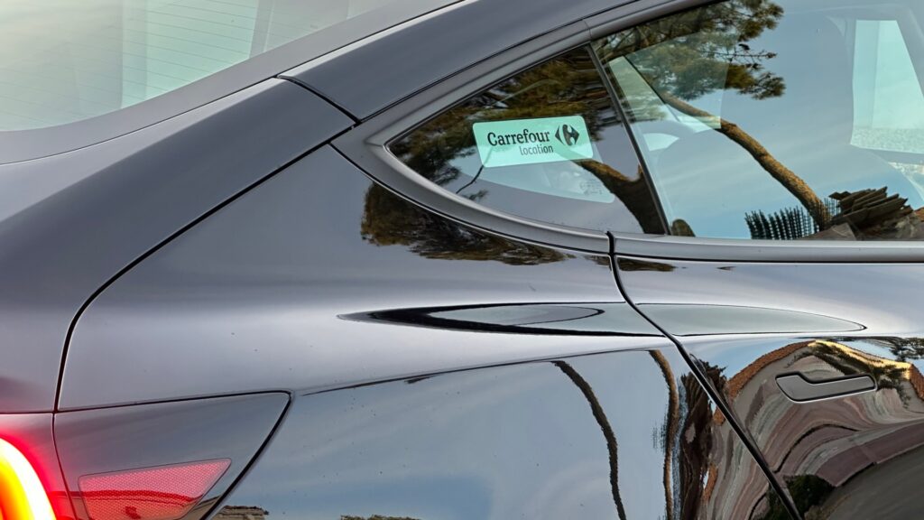 Sur la vitre arrière de la Model 3, il y a un autocollant Carrefour. // Source : Numerama