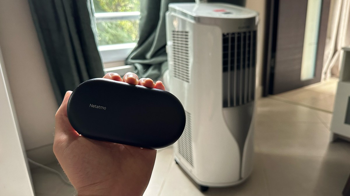 Le contrôle de clim connecté par Netatmo, à côté d'un climatiseur portable. // Source : Numerama