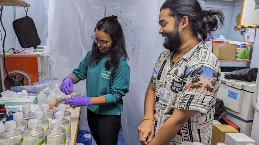 Les premiers auteurs, Diksha Sharma, à gauche, et Vignesh Menon, dirigent des expériences sur l'eau de mer recueillie dans le golfe du Maine lors d'une prolifération d'algues // Source : Annie Kandel