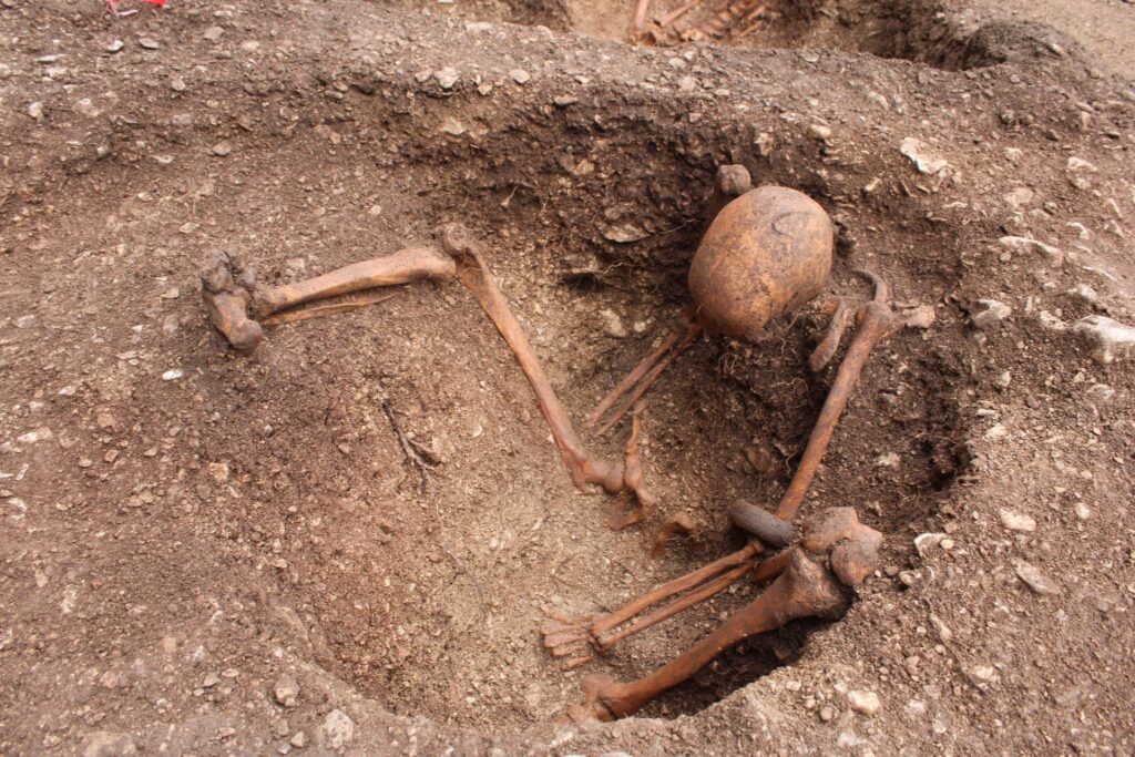 Inhumation d'un homme assis avec des stigmates d'une blessure au crâne et portant un bracelet en roche noire // Source : Hervé Laganier, Inrap