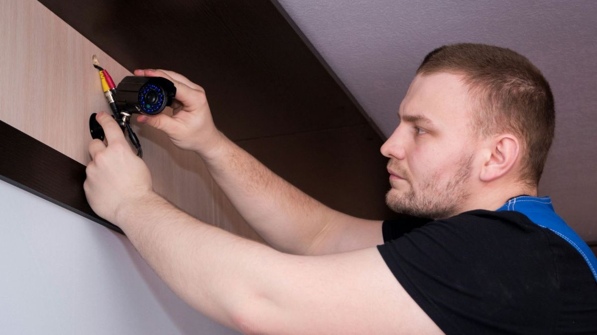 Un homme installe une caméra de surveillance // Source : Bermix Studio via Unsplash