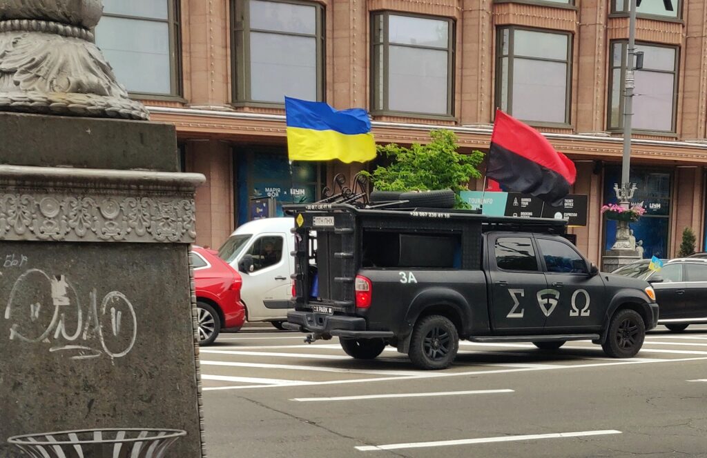 Voiture funéraire d'une brigade à Kyiv, avec le drapeau rouge et noir des résistants ukrainiens, de la musique martiale plein les haut-parleurs. Voiture funéraire d'une brigade à Kyiv, avec le drapeau rouge et noir des résistants ukrainiens, de la musique martiale plein les haut-parleurs.