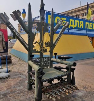 Le Trône de Fer en face de l'hôtel de ville de Kharkiv, en vrai matériel militaire, orné d'un trident ukrainien et d'une insulte envers Vladimir Poutine.