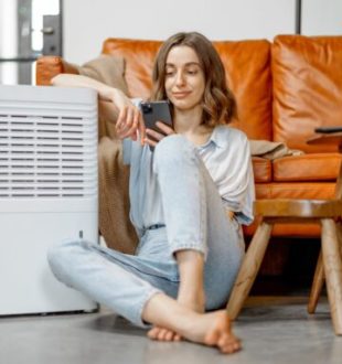 Une personne assise à côté d'un climatiseur. // Source : Envato