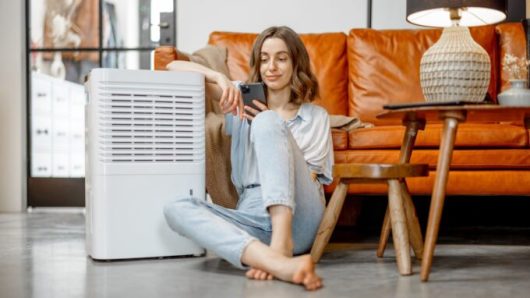 Une personne assise à côté d'un climatiseur. // Source : Envato