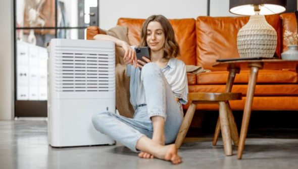 Une personne assise à côté d'un climatiseur. // Source : Envato