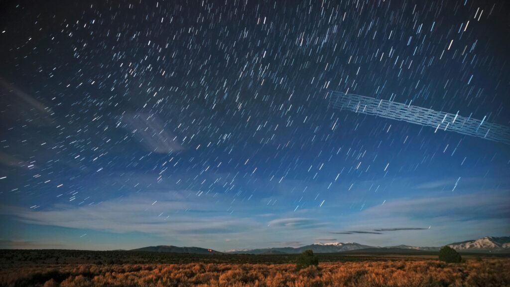 Un train de satellites Starlink photographi&eacute; peu apr&egrave;s leur lancement au-dessus de la for&ecirc;t nationale Carson (Nouveau-Mexique). // Source : Wikimedia/CC/Mike Lewinsky (photo recadr&eacute;e)