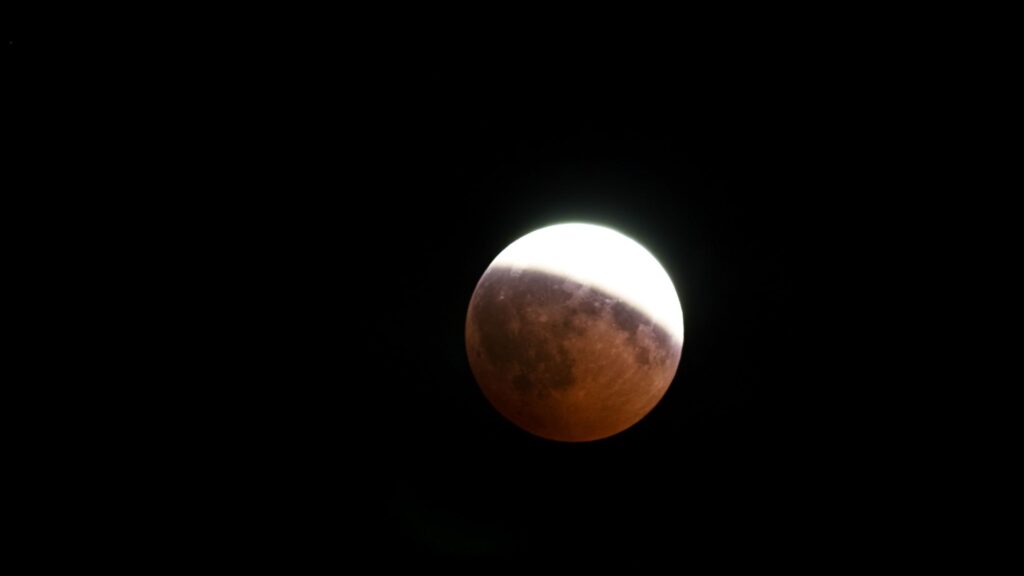 Éclipse partielle de Lune, seule la partie de l'astre se trouvant dans l'ombre prendre une teinte rougeatre. // Source : Canva