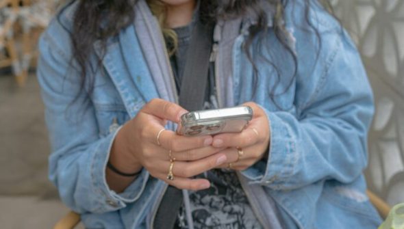 Une jeune femme avec un smartphone entre les mains // Source : Createasea via Unsplash