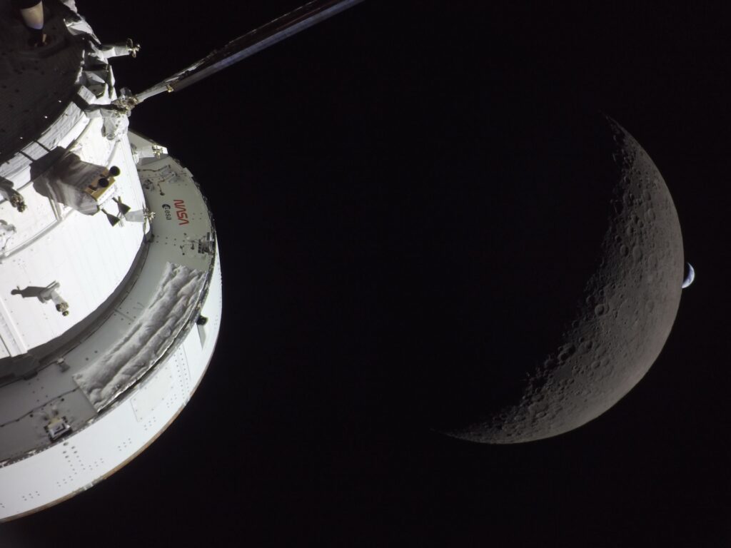 art002e009567 (April 6, 2026) - NASA&rsquo;s Orion spacecraft captures the Moon and the Earth in one frame during the Artemis II crew&rsquo;s deep space journey at 6:42 p.m. ET on the sixth day of the mission. The right side of NASA&rsquo;s Orion spacecraft is seen lit up by the Sun. A waxing crescent Moon is visible behind it. And then, a crescent Earth, tiny compared to the Moon, is about to set below the Moon&rsquo;s horizon on the right. Credit: NASA